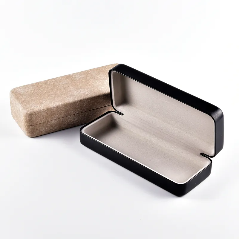 Open rectangular black hard shell eyeglass case with gray fabric lining, camel case in background
