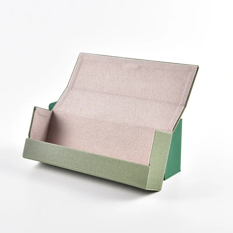 Magnetic eyeglass case shown open, revealing soft pink suede lining inside a sage green linen exterior