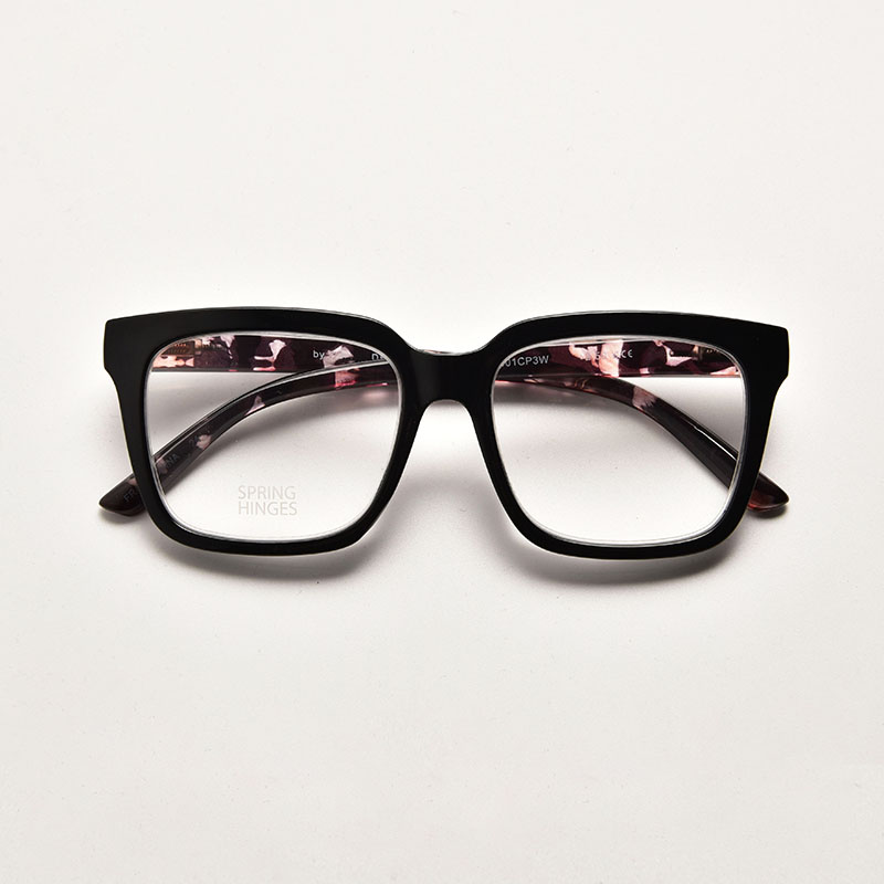 Chunky black square frame reading glasses featuring a unique floral pattern on the inner arms and flexible spring hinges for comfort.