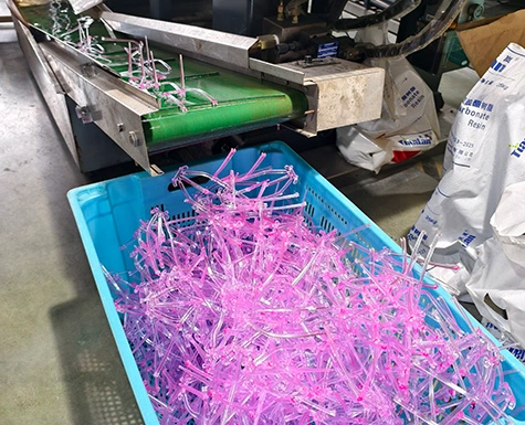 Mass production of plastic spectacle frames dropping into collection crates on the factory floor.