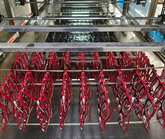 Ultrasonic cleaning process for red eyeglass frames on the factory production line.